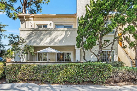 Front view of a multi-story building with a balcony and staircase.