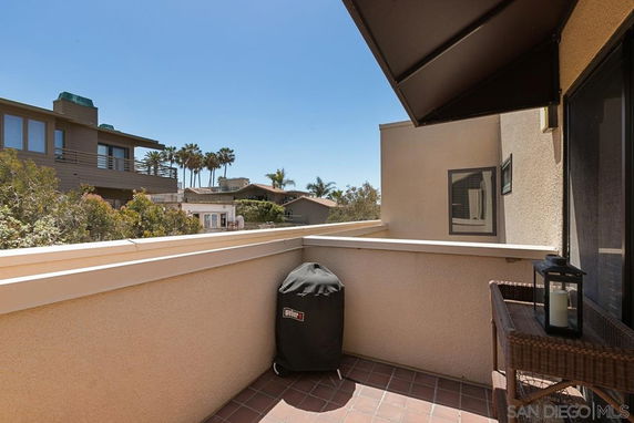 Outdoor balcony area with a view of nearby houses and trees