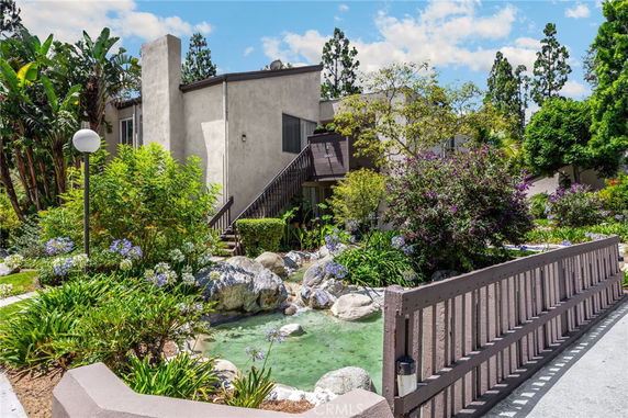 Front view of a two-story building with a landscaped garden and a wooden bridge.