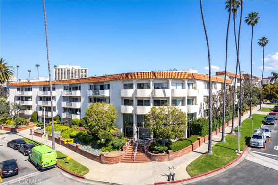 Front view of a multi-story residential building with balconies and tiled roof.