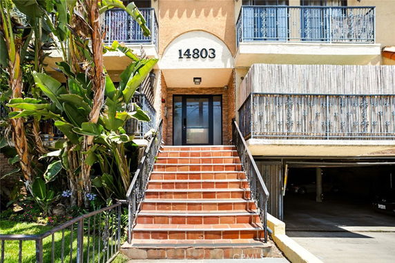 Front view of a building entrance with stairs and balconies.