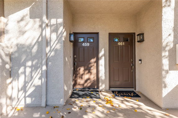 Front view of two adjacent doors with numbers 459 and 461, in a stucco building.