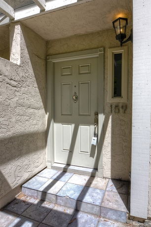Entrance view of a house with a beige front door and a small window beside it.