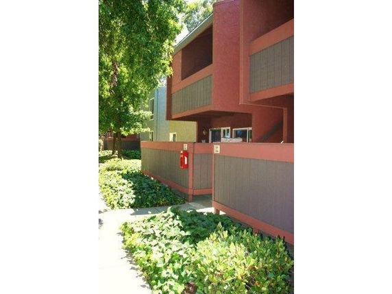 Exterior view of a multi-story building with balcony and pathway.