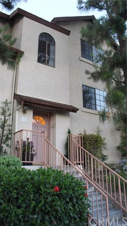 Front view of a multi-story house with a staircase leading to the entrance.