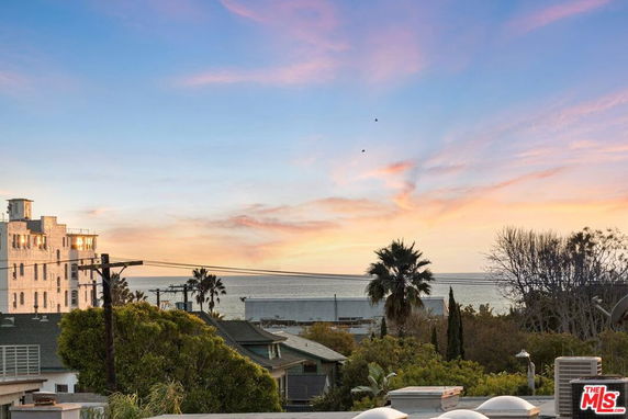 Panoramic view of the coastline with buildings and trees in the foreground at sunset.