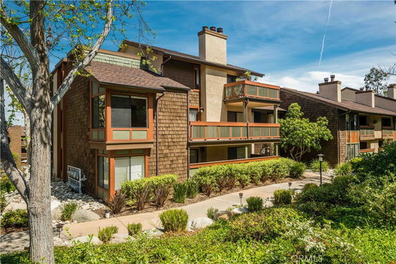 Front view of a multi-story residential building with balconies and wood siding.