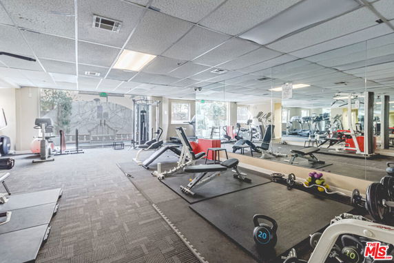 Indoor gym area with various fitness equipment and mirrored walls.