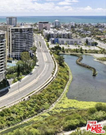 Aerial view of a coastal urban area with roads, buildings, and a waterway.