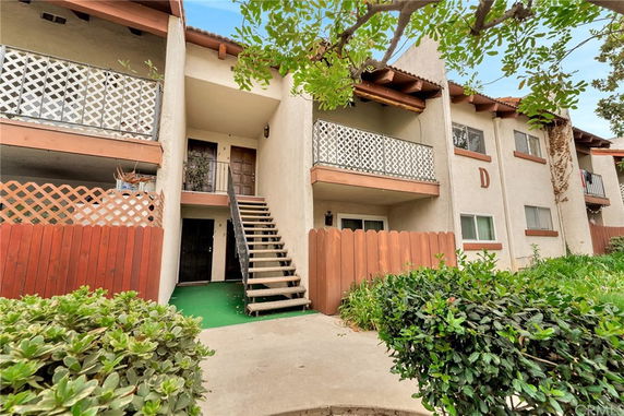 Front view of a two-story apartment building with balconies and external staircase.