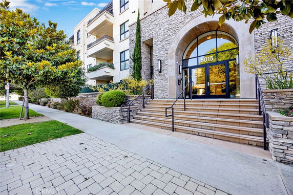 Front view of a multi-story building with stone facade and large glass entrance.