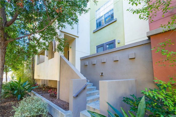 Front view of a multi-story residential building with a staircase leading to the entrance.