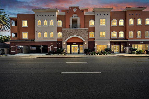 Front view of a multi-story building with an arched entrance and illuminated windows.