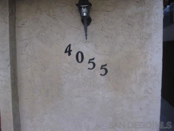 Front view of a building wall with the number 4055 and a wall-mounted lamp.