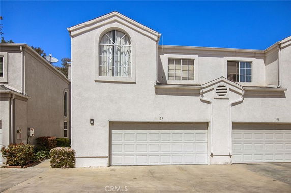 Front view of a townhouse with a double garage and arched window.
