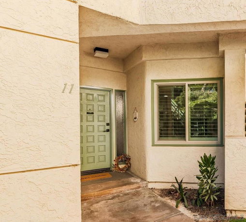 Front view of a house entrance with a light green door and adjacent window.