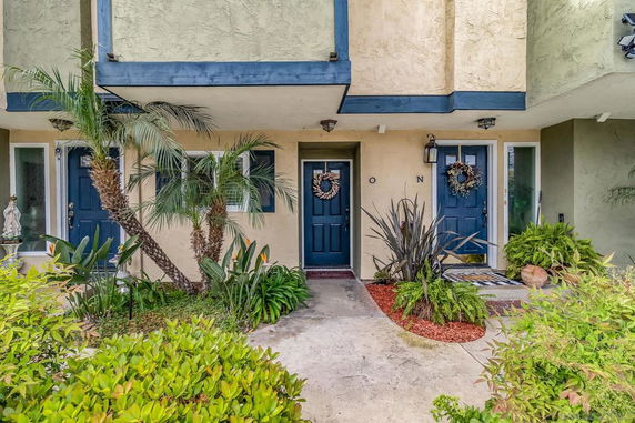 Front view of a two-story residential building with blue doors and decorative wreaths.
