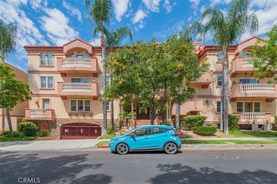 Front view of a multi-story residential building with balconies and a central entrance.