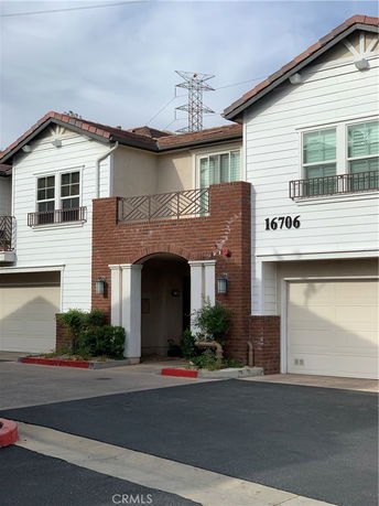 Front view of a two-story house with a brick and white exterior, featuring multiple garages.