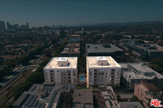 Aerial view of two adjacent multi-story apartment buildings with a cityscape in the background.