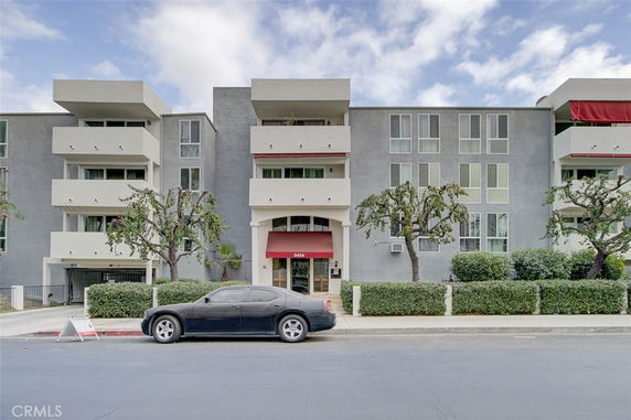 Front view of a multi-story apartment building with balconies and a central entrance.