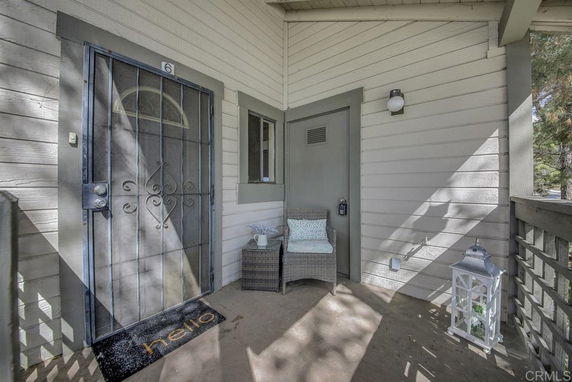 Front view of a house entrance with a security door and a small seating area.