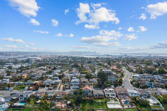 Panoramic view of a residential area with numerous houses and a cityscape in the distance.