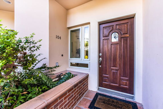 Front view of a house entrance with a wooden door and window beside it.