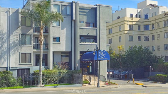 Front view of a multi-story apartment building with a blue entrance awning.