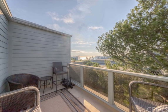 Balcony with outdoor seating and view of surrounding area including trees.