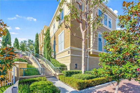 Front view of a two-story beige building with multiple windows and surrounding greenery.