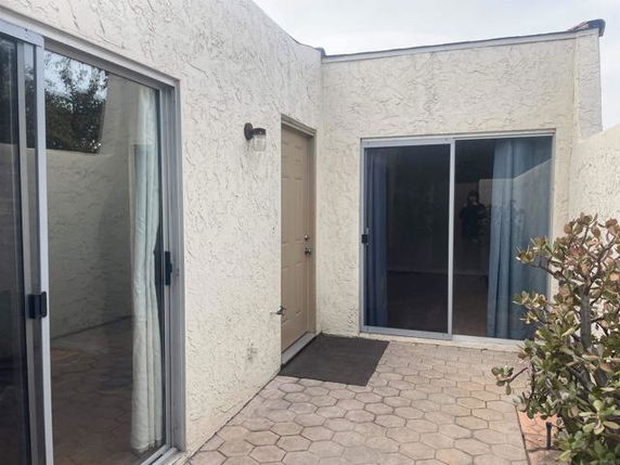 Exterior view of a small building with sliding glass doors and stucco walls.
