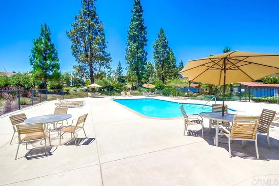 Outdoor swimming pool area with lounge chairs and umbrellas.