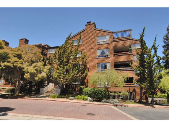 Front view of a multi-story residential building with wooden exterior and balconies.