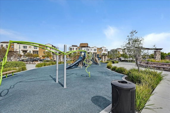 Outdoor playground with slides and climbing structures, surrounded by residential buildings.