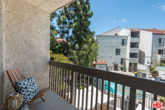 View from a balcony overlooking apartment buildings and a swimming pool.