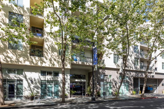 Front view of a multi-story residential building with balconies and glass doors.