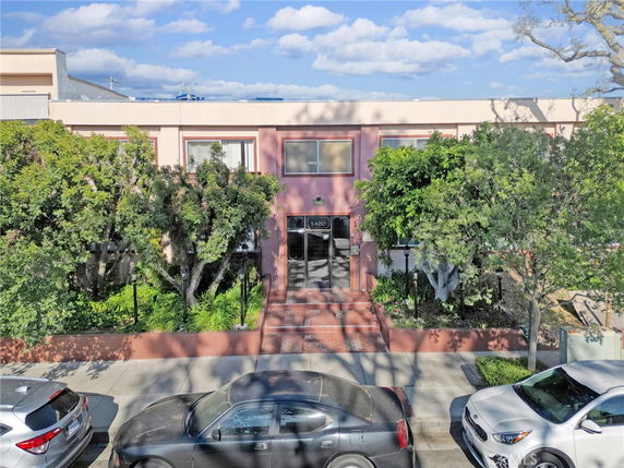 Front view of a two-story building with trees and shrubs at the entrance.