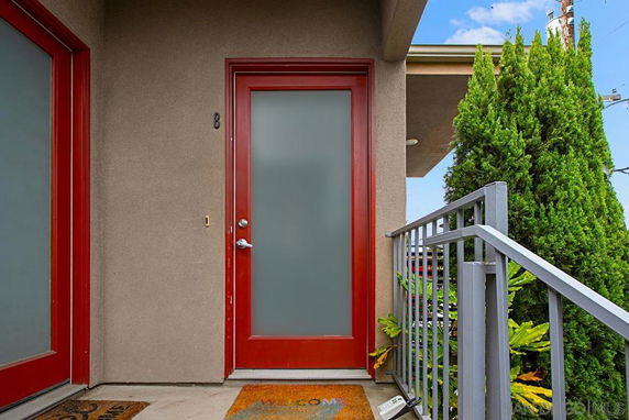 Front view of an entrance with a red door and frosted glass panel.