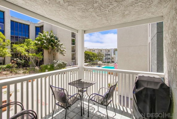 View from a balcony overlooking a pool area and other buildings.
