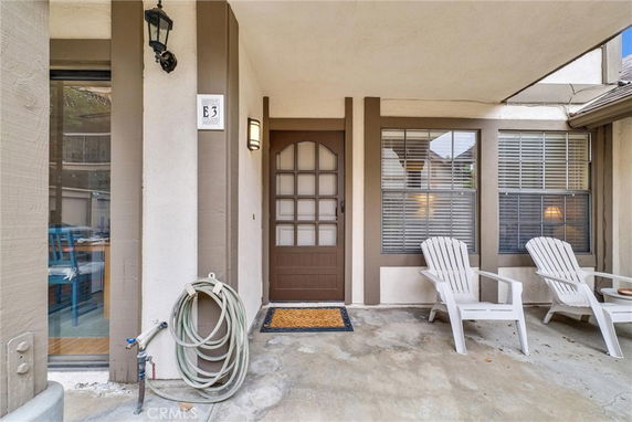 Front view of a house entrance with a brown door and two windows.
