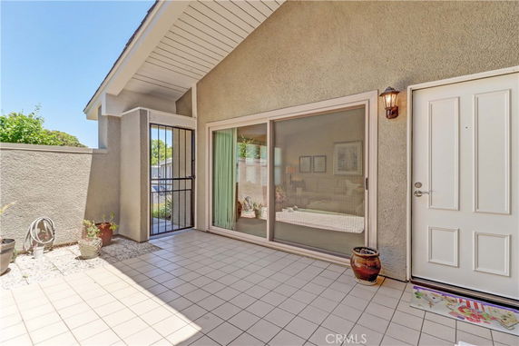 Front view of a house with a tiled patio and sliding glass door.