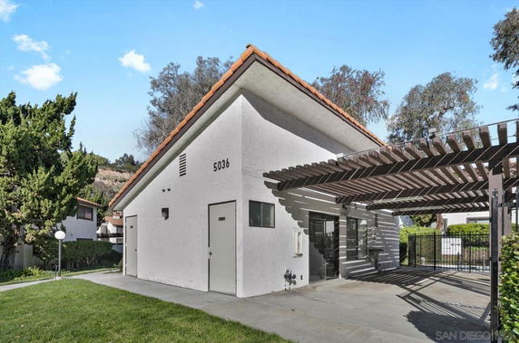 Front view of a building with a sloped roof and attached pergola.