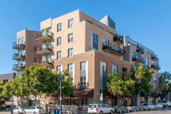 Front view of a multi-story building with balconies and ground-floor commercial space.