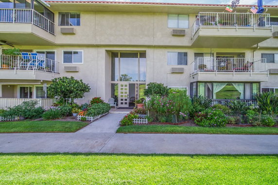 Front view of a multi-story residential building with balconies and landscaped garden.