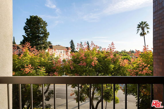 View from a balcony showing trees and surrounding buildings.