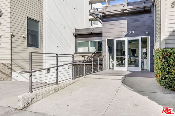 Front view of a modern building entrance with glass doors and an access ramp.