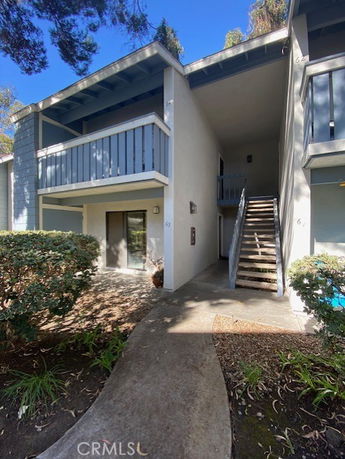 Front view of a multi-story apartment building with external staircases and balconies.