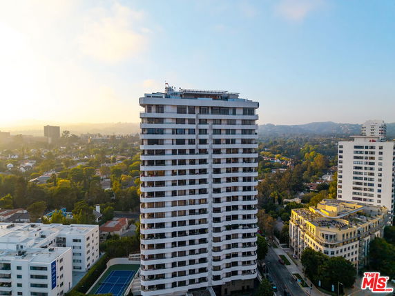 Front view of a tall residential building with multiple balconies.