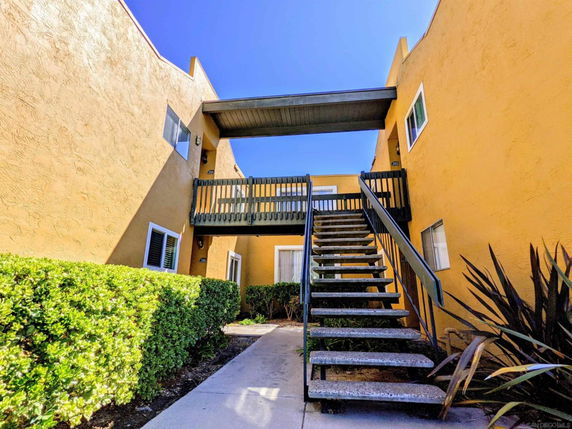Front view of a building with an external staircase and yellow walls.